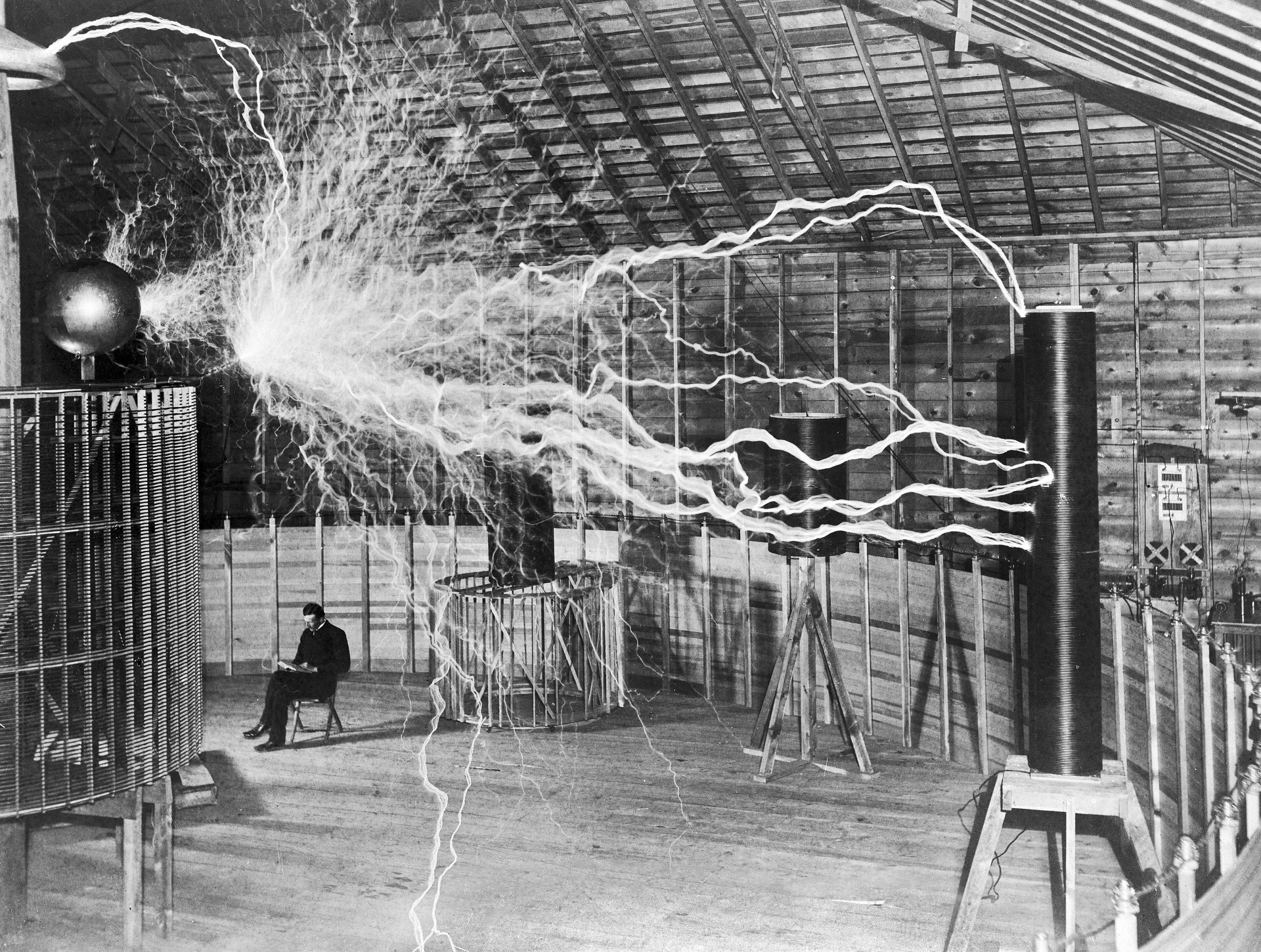 Nikola Tesla seated beneath artificial lightning at Colorado Springs