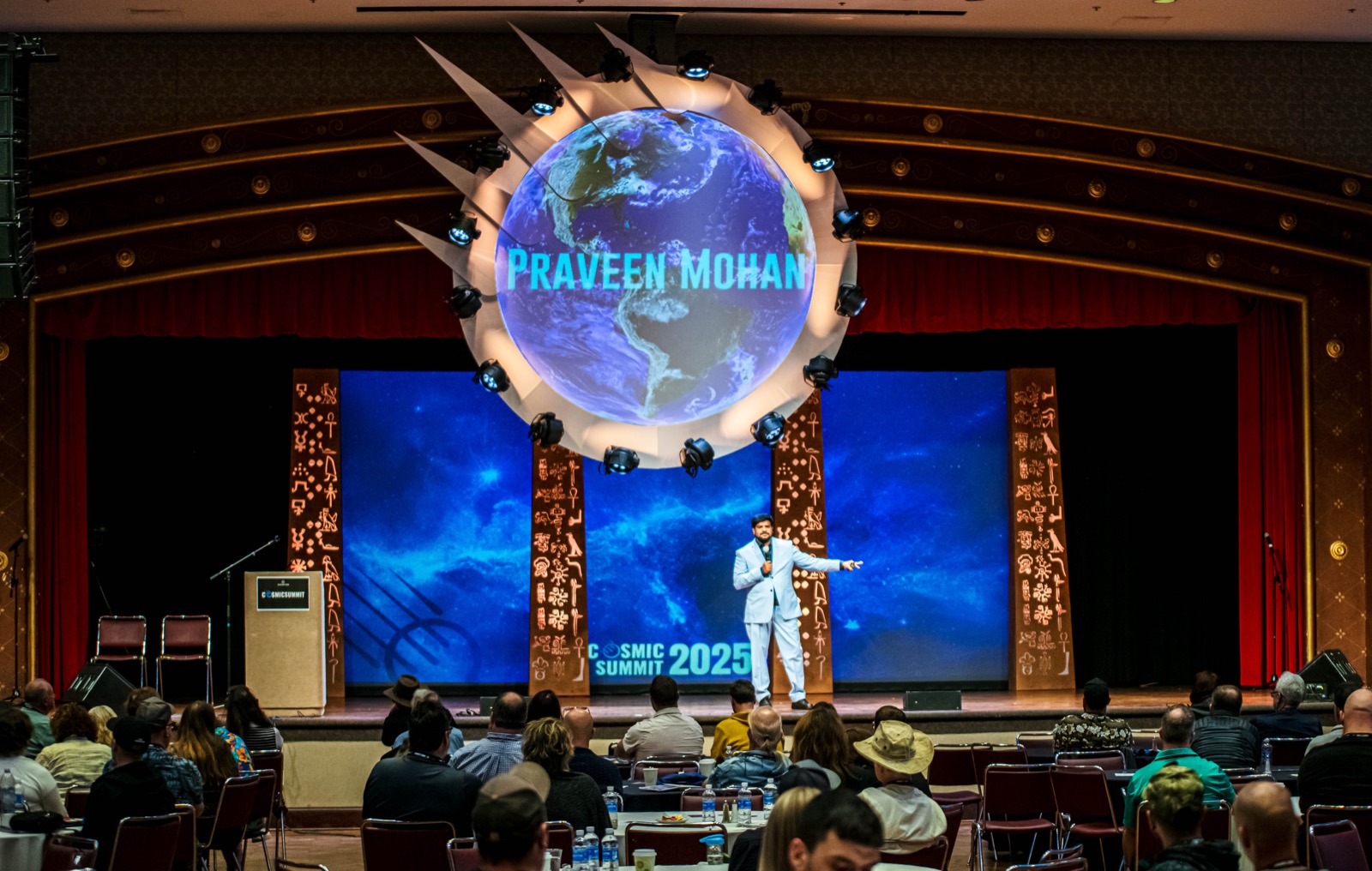 A speaker beneath the impact rig at Cosmic Summit 2025